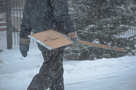 公共服务市政服务的一名工作人员带着雪铲在暴风雨 暴风雪或冬季降雪中在城市的恶劣天气中沿着道路行走 北方的极端冬季天气条件落雪气氛预测景观背景