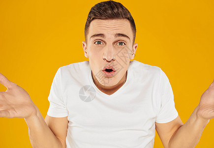 一个穿白色T恤衫的男人 用黄色背景情绪模式 将双臂伸向两侧工人管理人员微笑商业海报广告牌手指卡片工作人士图片