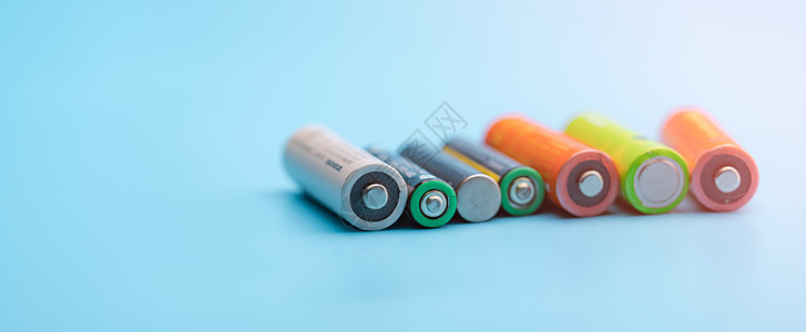 在蓝色背景的充电电池 可充电锂离子电池的选择性聚焦负端子 AA 和 AAA 尺寸的旧锂离子电池 电池回收概念 绿色能源释放阴极细图片