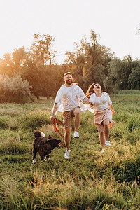 大狗跟一个男人和一个女孩散步夫妻跑步晴天绿色乐趣棕色飞盘皮带男人朋友图片