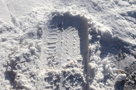 近距离观察积雪覆盖的街道上的轮胎痕迹雪堆曲目运输天气阳光蓝色摄影季节车轮小路图片