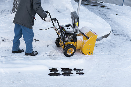 暴风雪过后 男子用造雪机清理车道 在街道上工作的除雪设备 从雪中清理街道 正在下雪风暴鼓风机机械男性打扫拖拉机机器降雪男人人行道图片