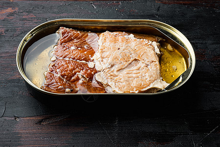 野生阿拉斯加鲑鱼罐头熏鱼 用锡罐 用旧的黑木制桌底罐头产品背景盘子贮存鳟鱼桌子养护营养食物图片