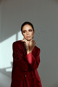化妆品广告黑发红色 有明亮的化妆品 手握在面容光鲜时装服装红色夹克上背景