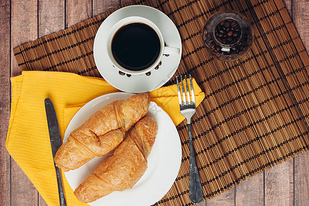 餐桌上早餐甜点上盘子上的新鲜羊角面包桌子食物美食黄油饮料咖啡小吃杯子木头咖啡店图片