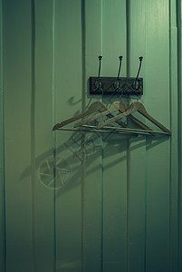 棕色木衣架 木墙背景上的金属钩上挂着阴影 白色复古房间里的空衣架 挂钩安装在黑暗房间的木墙上 田园风试衣间图片