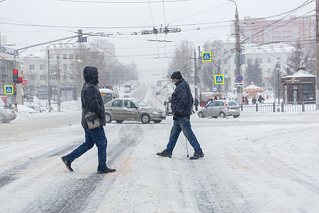 俄罗斯图拉-2020年2月13日 两人在大雪降下时穿越城市道路图片