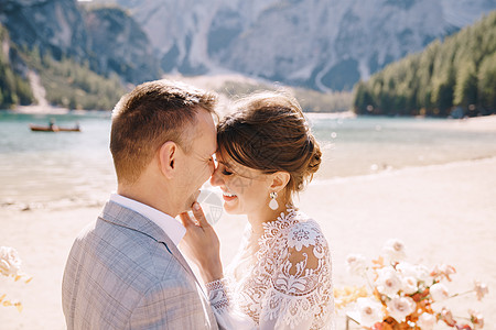 新婚夫妇在意大利布拉埃斯湖的背景下 以秋天的花柱拱门为仪式现场亲吻 在欧洲的目的地婚礼 在 Braies 湖上丝带新娘干花套装树图片