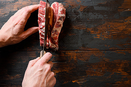 大理石牛排 切肉板的恰克眼卷 有机牛肉 屠夫手和肉刀在工作排骨上图片