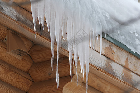 大冰柱挂在原木屋顶上 冬霜和泉水滴空气日志乡村生态房子图片