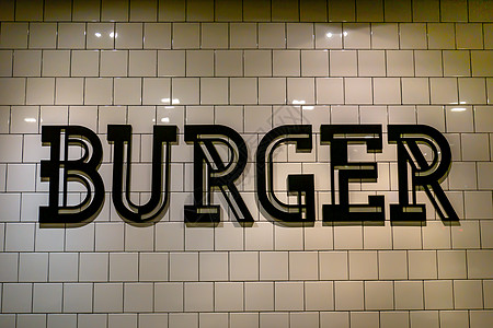 瓷砖地板墙背景上用黑色字母写汉堡的标牌图片