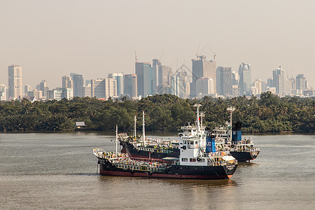 两艘货轮停在河中央 位于Chao Phraya河旁的绿树前面商业地标货物天际港口旅游血管旅行景观天空图片