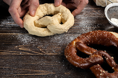 制作retzel的分步骤说明 厨师推出面团 并推出pretzel 黑暗背景母猪洋葱脂肪木板面条打样碎肉黄油糕点酵母背景图片
