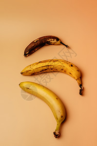三个香蕉的丑陋果实从成熟变成更腐烂的棕色 有孤立的斑点 水果的概念是卖不了超市的 垂直方向图片