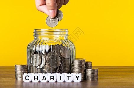 玻璃罐中有很多有黄色背景的硬币 拯救慈善概念团队慈善事业捐赠机构玻璃生活桌子商业标签现金图片