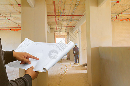 工程师手指点在纸质计划蓝图上 检查建筑技术人员所在的建筑工地墙壁内部 并附有复制空间添加文本图片