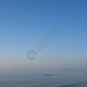 平静的蓝色大海 蓝色天空下有一个小波浪图片