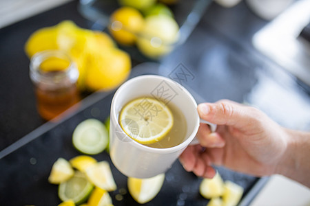 雄手握着一杯柠檬茶 在水果片上方图片