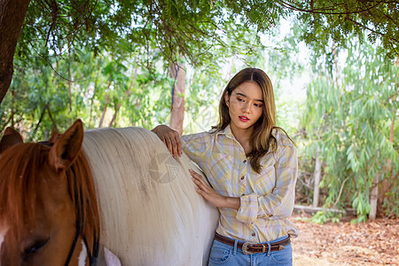 一名身着女牛仔风格的妇女坐在西部农场环境的马场里草地骑师女士友谊女孩农场骑士骑术农村荒野图片