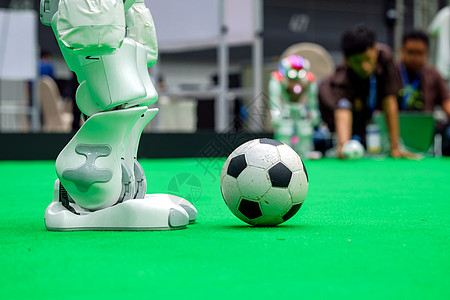 近近右腿足球机器人 在足球赛场踢足球的足球运动员背景
