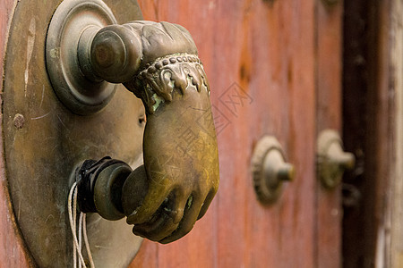 一只手形状中的老Brass Door敲钟手治具木头圆圈家居硬木静物金属门把手五金古董背景图片