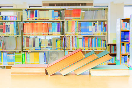 旧书红绿色 学校图书馆在木制桌子上的堆积专著 模糊的书架背景 教育学习概念与复制空间添加文字内容;图片