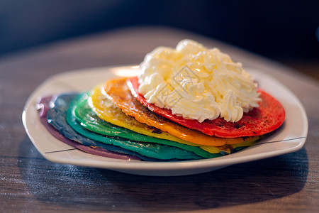 一张盛满一堆彩色煎饼和奶油在顶端的板块饼子食谱早餐小吃美味甜度午餐食物盘子彩虹图片