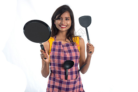 以白色背景持有厨房用的年轻印度妇女SPO STPULA 拖拉机和锅等女孩平底锅肩胛骨餐具食物用具衣服金属勺子女性图片