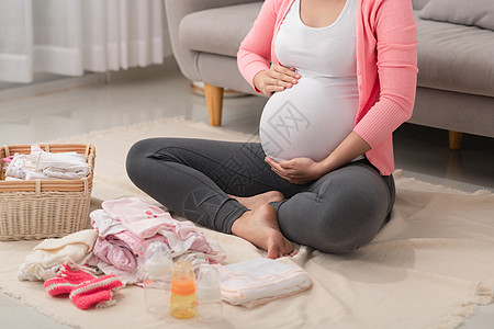 美丽 怀孕的亚洲孕妇 为孕妇新出生婴儿包装和准备篮子中的婴儿衣物母亲家庭肚子母性身体衣服女士图片