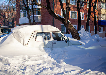 冬季的一辆客车在暴风雪后被雪覆盖庭院漂移城市冻结雪堆季节街道寒冷降雪完全地图片