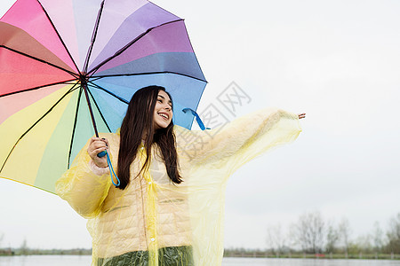 美丽的黑发美女 在雨中拿着多彩的雨伞季节快乐成人天气下雨乐趣幸福雨衣微笑城市图片
