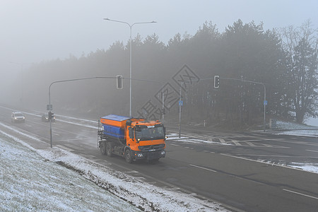 雾路雪犁卡车 冬天时有雾和交通背景