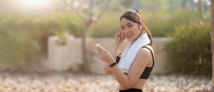 一位美丽的亚洲年轻健身女子在户外跑动 用耳机监听音乐的照片电话音乐播放器身体有氧运动健康慢跑者训练跑步运动员女士图片