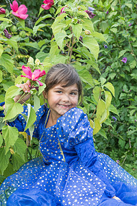 微笑的可爱小女孩在盛开的木上的肖像图片