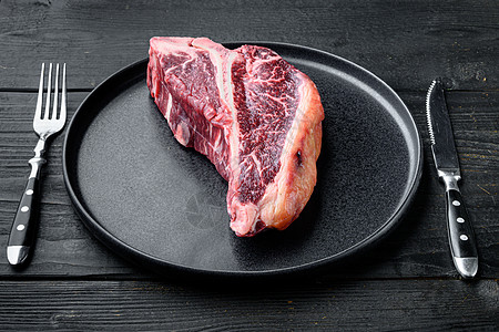 意大利骨干 年老牛肉肉牛排 盘上 黑木桌背景图片