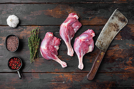 菜鸭腿 准备用旧屠宰刀烹煮的家禽肉 在老黑木桌背景上 顶层视野铺平图片