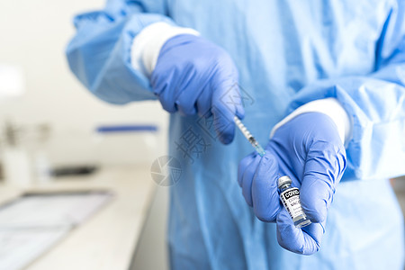 全球疫苗接种抗击 Covid-19 大流行病的概念 身着全套防护装备 带蓝色手套的医疗或卫生工作者准备注射药物 用注射器从小瓶中图片