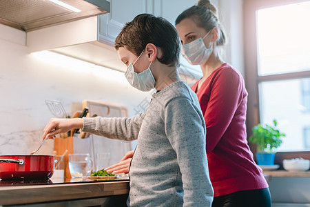 危机时期母子在家做饭厨房面具防护服母亲家庭口罩儿子孩子安全烹饪图片