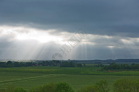 户外旅行德国附近的田地覆盖着风云中美丽的乡村和阳光绿色植物天空场景环境季节农场爬坡晴天地平线太阳光线背景