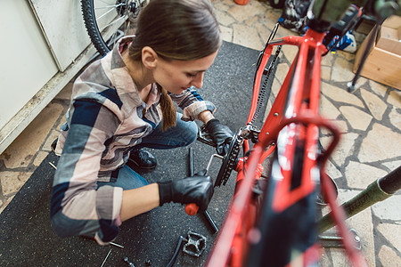 自行车技术员在她的车间里骑自行车齿轮店铺服务工作机械职业女士作坊生意维修图片