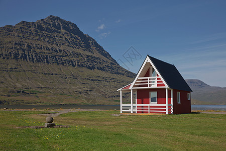 在冰岛东部爱斯基菲约尔杜尔背景中拥有强大的Holmatindur山的传统红漆木板房吸引力海岸村庄支撑海岸线蓝色冰川地标海洋旅行图片