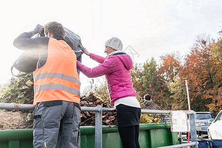 在回收中心用集装箱中施放废绿色的汞和男人女士工人收藏收物回收场废物废料收集垃圾分类图片