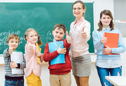 学生和老师在学校玩得开心时 用拇指显示成绩房间职业瞳孔教学学习小学女士图书课堂男孩们图片
