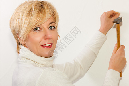 女人把钉钉钉在墙上金发指甲工人女性房子驾驶别针锤子图片