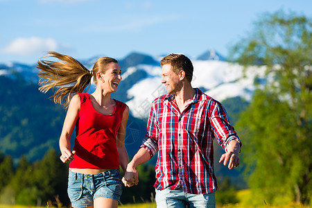 一对夫妇在草地上奔跑 与山峰远足者恋爱山脉登山鞋朋友们假期女朋友跑步享受自由图片