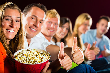 人们在电影院看电影 玩得开心微笑友谊男性金发观众电影成人思维乐趣爆米花图片