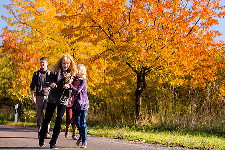 秋天家庭在多彩树木前行走爸爸街道女儿晴天姐姐女儿们姐妹阳光妈妈孩子图片