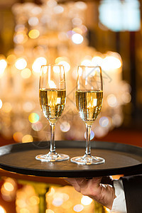 服务员在餐厅把香槟杯放在餐盘上枝形托盘美食气氛庆典男人背景香槟奢华服务图片