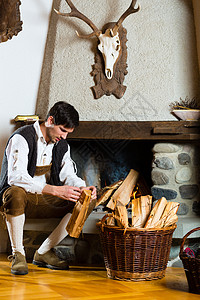 北欧客厅猎人小屋或高山小屋里的年轻人男性男人空闲品牌木屋时间客厅乡村戏服壁炉背景