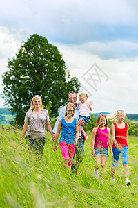 幸福的家庭在草原上行走母亲姐姐阳光兄弟姐妹天空丈夫太阳草地爸爸父亲图片